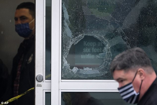 Police say they came upon the male suspecting assaulting a woman and opened fire, killing the man. Pictured: a broken glass door is scene at the Burlington Coat Factory
